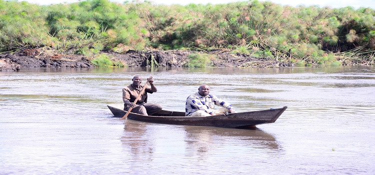 Hon. Moses Kabuusu crossing from one side of the Villa-Maria, Kyamulibwa- Kabulasoke Road with a canoe