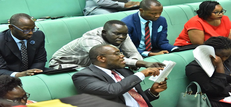 Shadow Attorney General, Hon. Wildred Niwagaba shows Hon. Oguzu Lee a provision in the bill